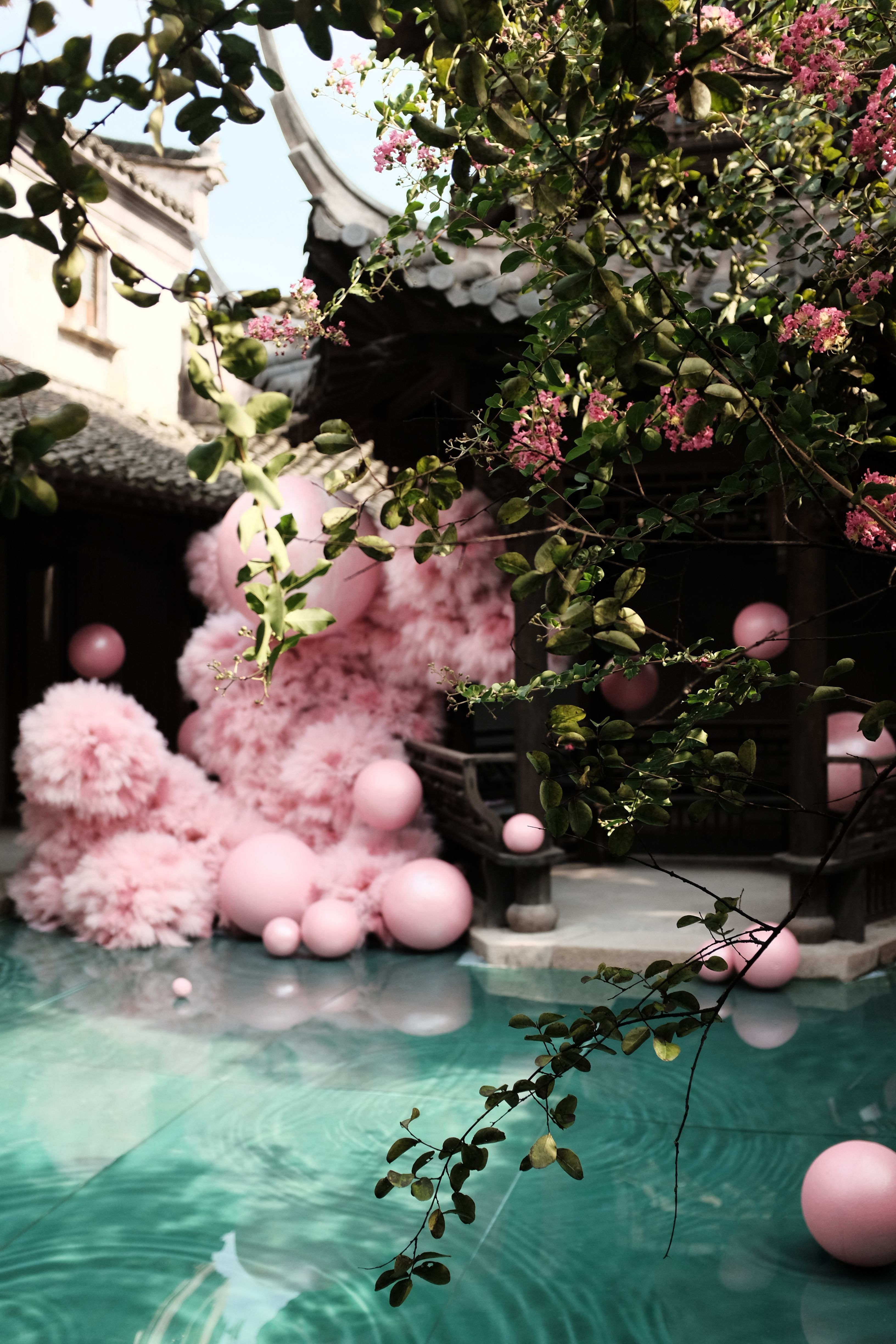 Elegant courtyard featuring a vibrant pink floral sculpture over a tranquil pool, creating a dreamlike ambiance.
