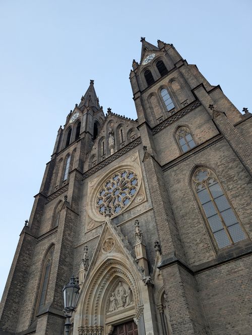 Free A detailed view of a Gothic cathedral's facade showcasing a large rose window under a clear sky. Stock Photo