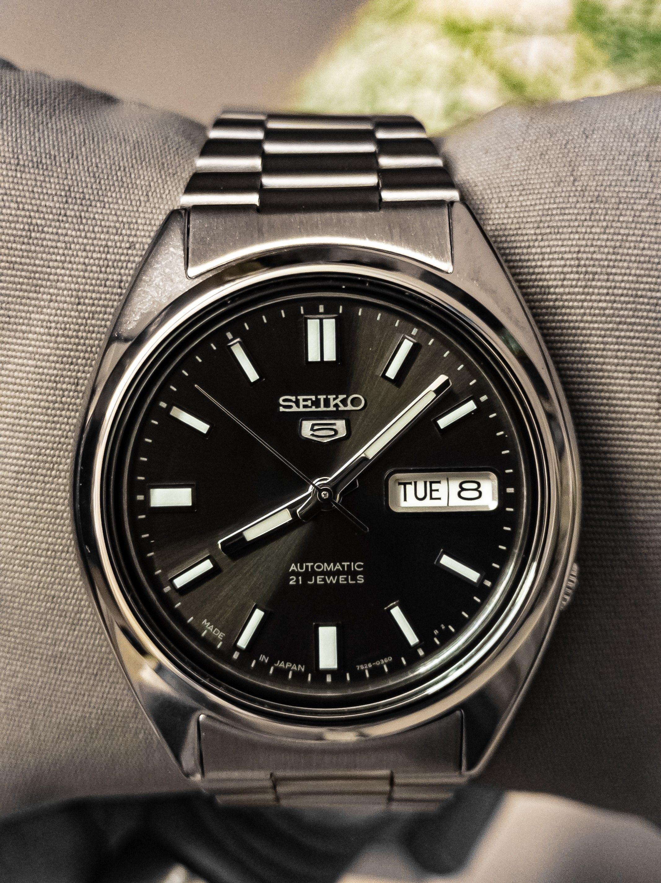 Primer plano de un Seiko 5 automático con fecha y brazalete metálico.