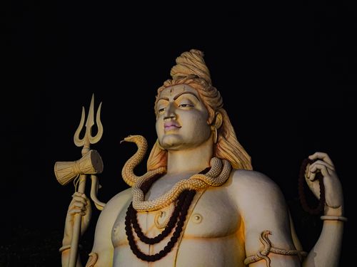 Free A striking statue of Lord Shiva illuminated against a dark night sky, depicting Hindu cultural iconography. Stock Photo