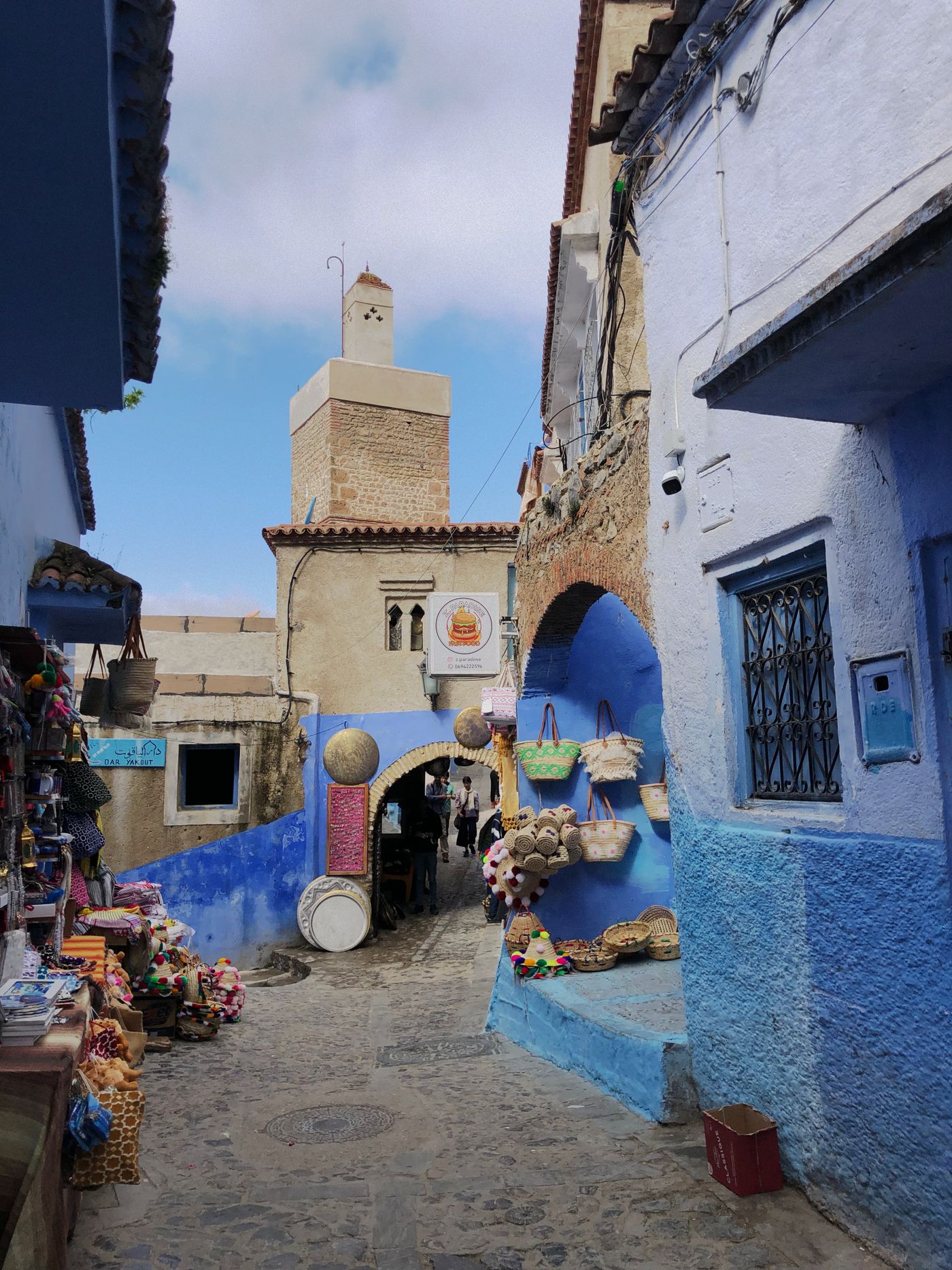 Blue street in Chefchaouen with colorful market stalls and baskets