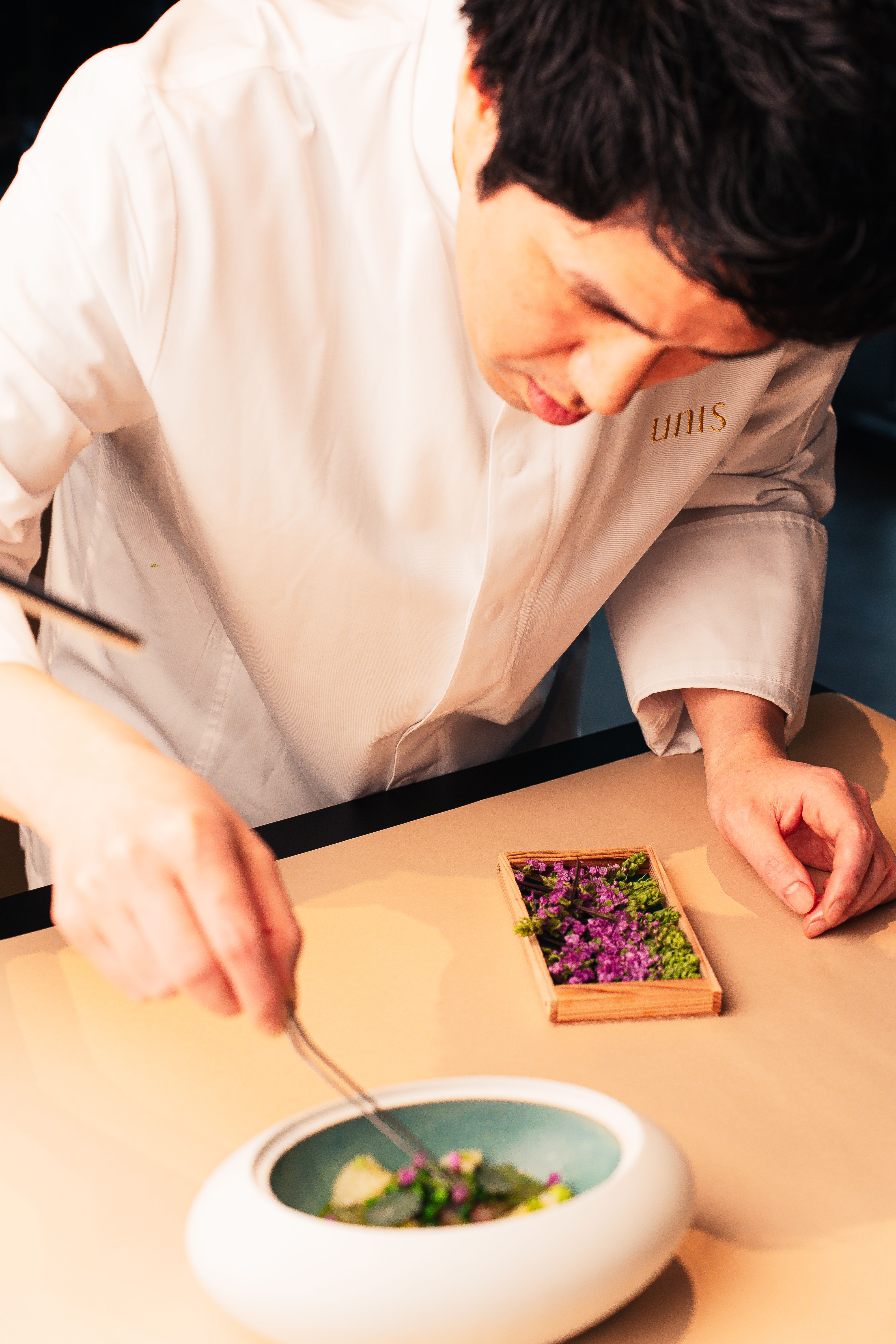 Chef delicately prepares a modern dish in a Tokyo restaurant, showcasing culinary artistry.