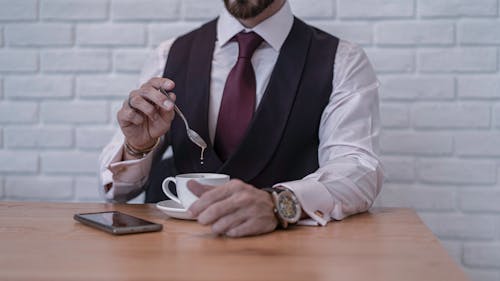 Homem De Terno Preto E Camisa Branca De Manga Comprida Segurando Uma Colher De Prata