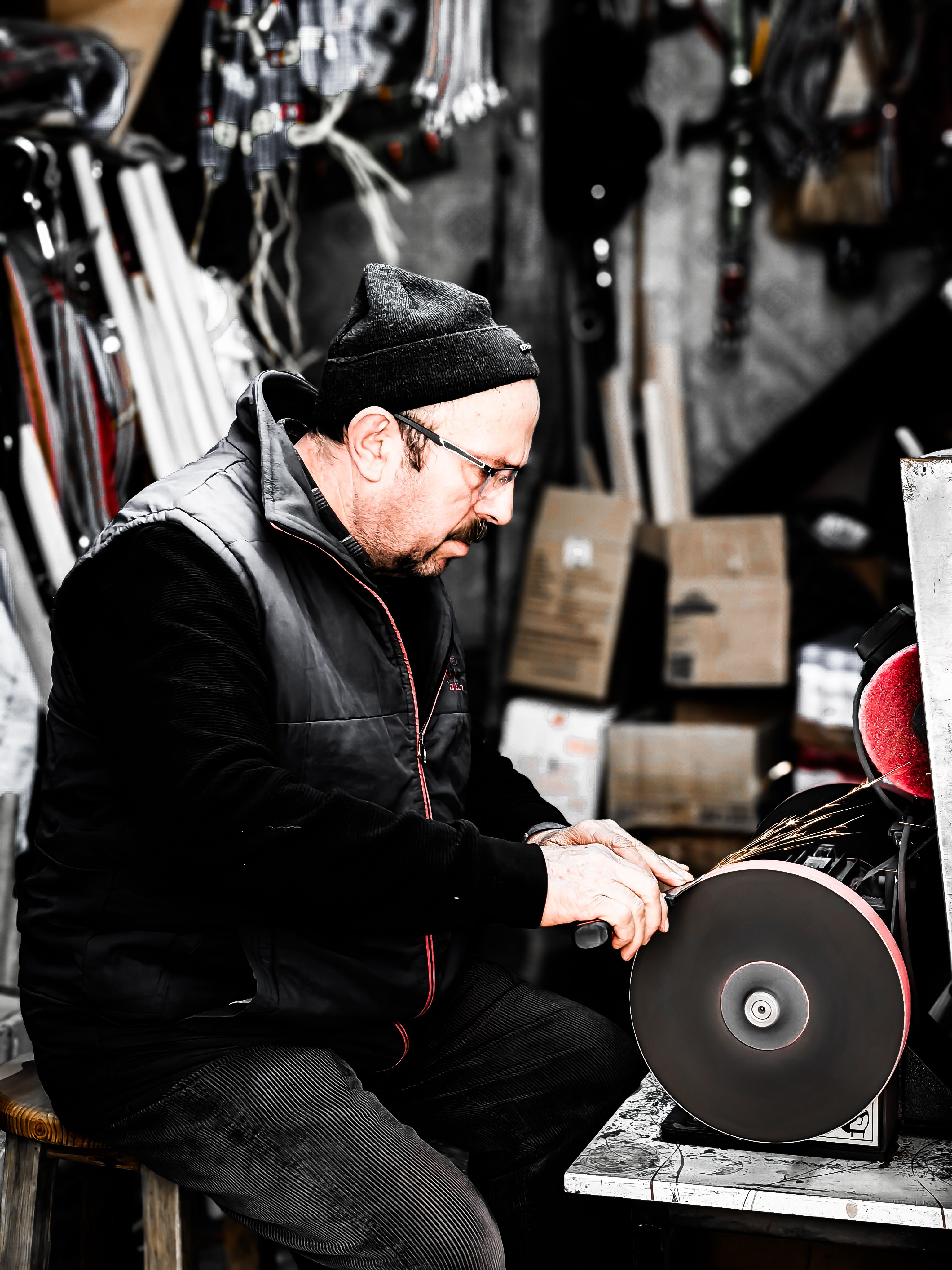 Adult craftsman sharpening tools on a grinder in a workshop, Amasya, Türkiye.