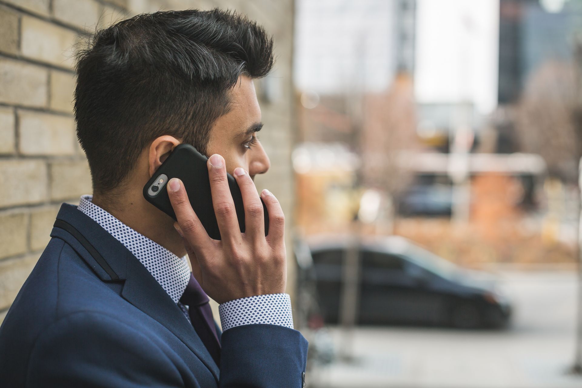 Professional man in suit making a phone call outside in city setting.