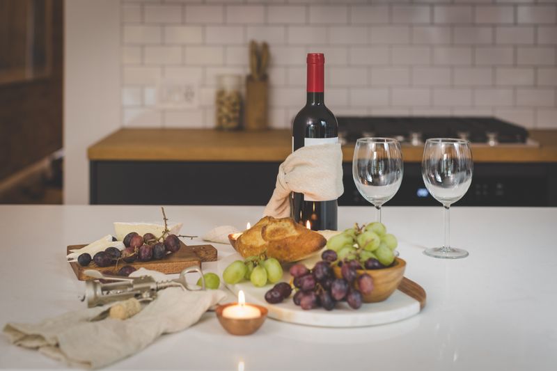 Wine bottle wrapped in linen with grapes, bread and glasses — photo by Burst on Pexels