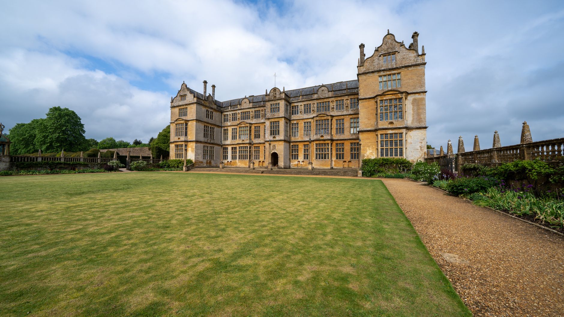 Stunning view of a grand historical manor in England with pristine gardens