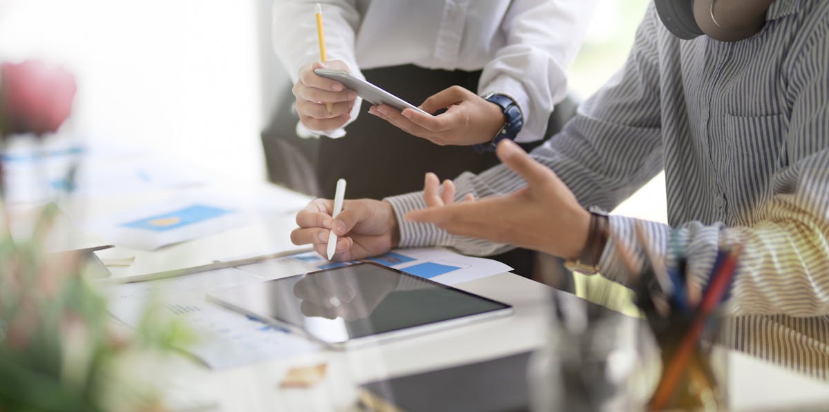 Overhead shot of a student writing notes while listening to music on a laptop