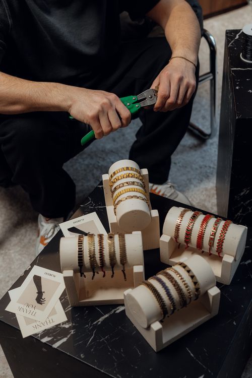 Free Close-up of artisan crafting bracelets with tools in a workshop. Detailed craftsmanship and design displayed. Stock Photo