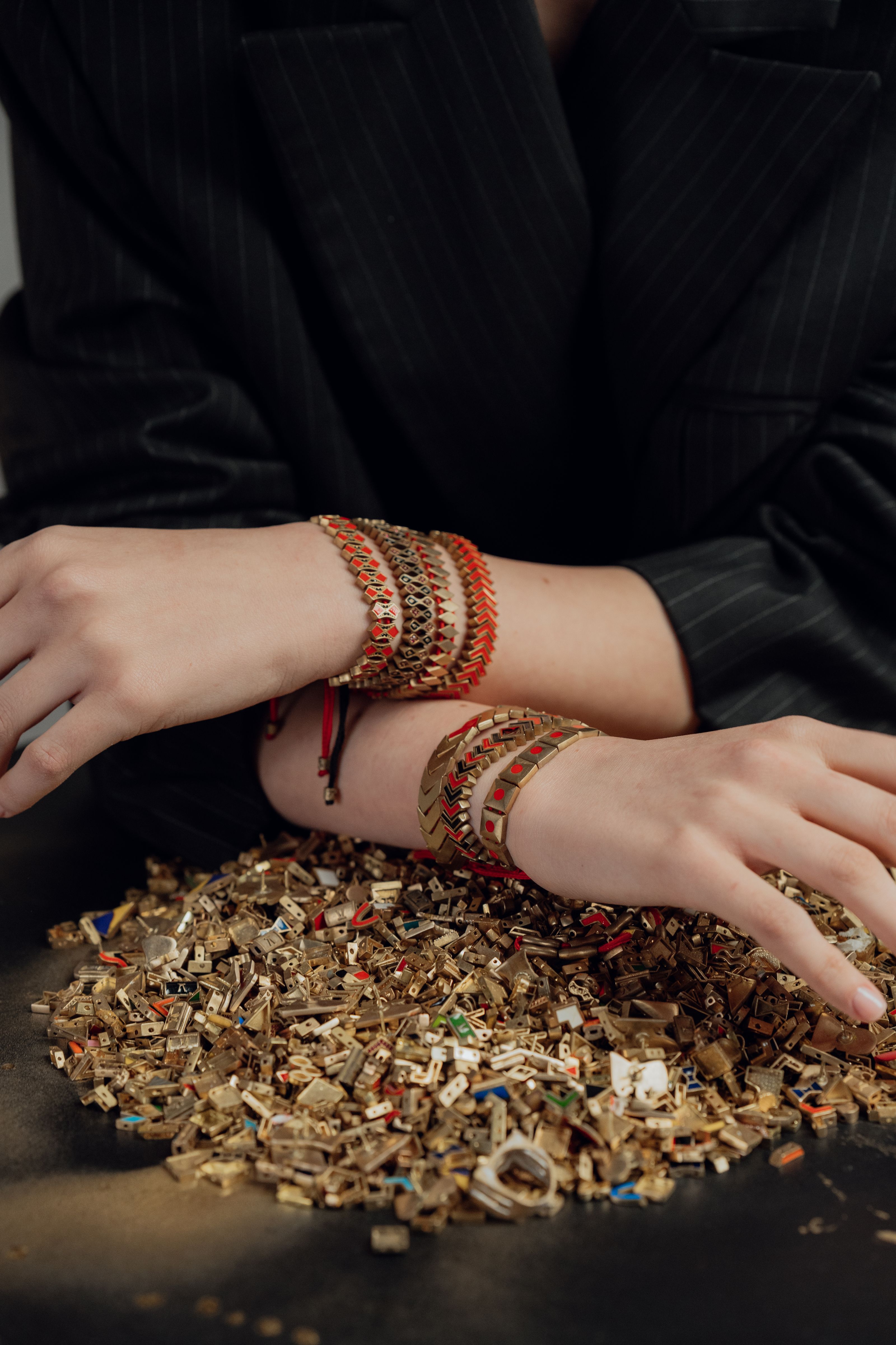 Pulseiras elegantes nos pulsos sobre uma superfície decorativa com elementos de ouro fragmentado.