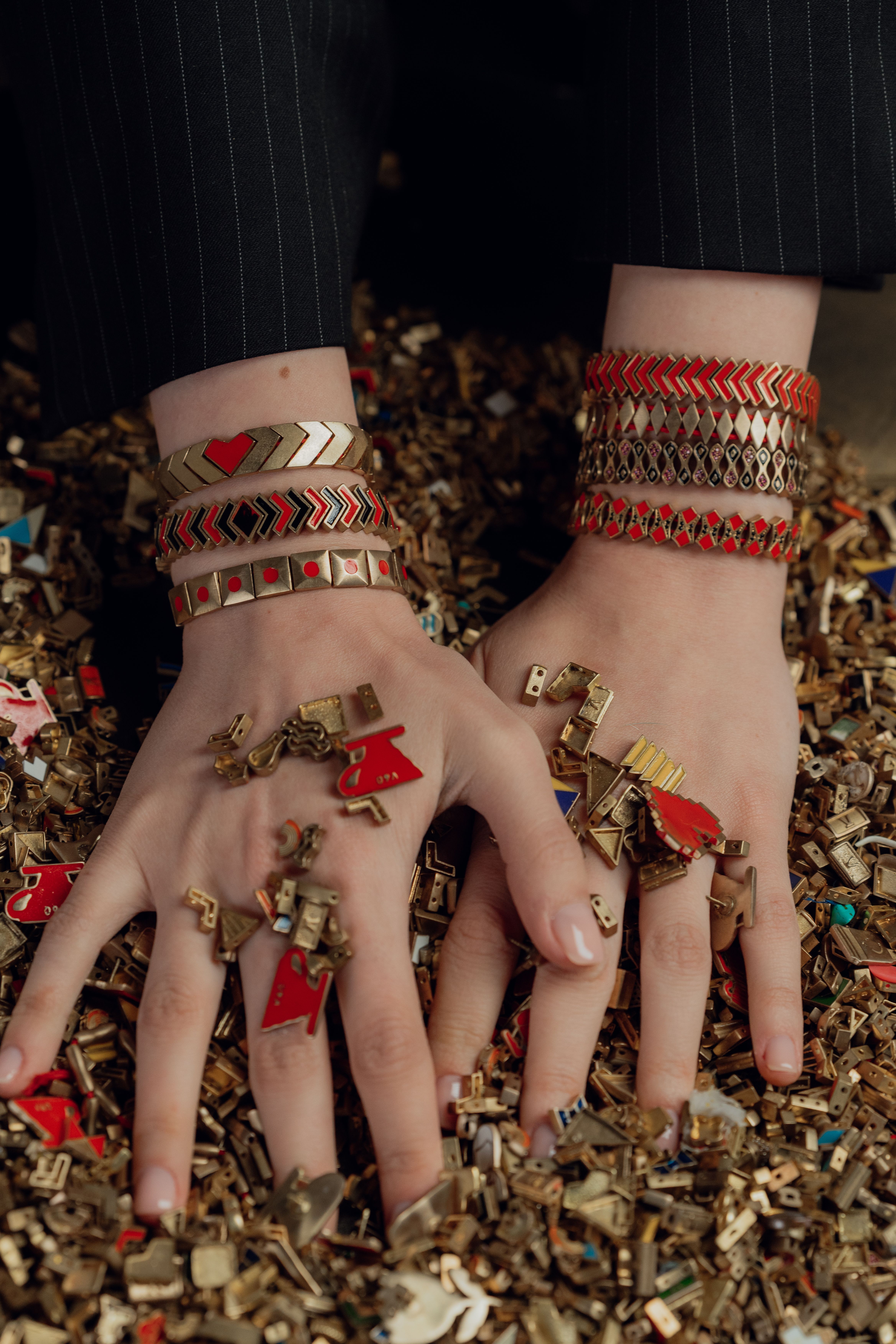 Close-up of hands adorned with stylish bracelets on a textured background, featuring modern fashion jewelry.