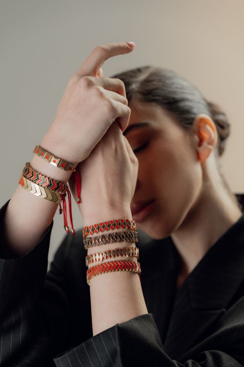 Free A woman in a dark suit showcasing colorful bracelets on her wrist in a contemplative pose. Stock Photo