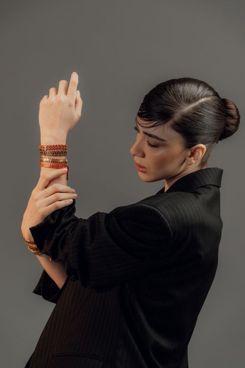 Free Stylish woman in a black suit poses with her hand adorned with bracelets, showcasing elegance and fashion. Stock Photo