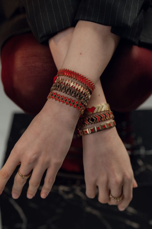 Free Close-up of a person's wrists adorned with gold and red bracelets, showcasing modern fashion jewelry. Stock Photo