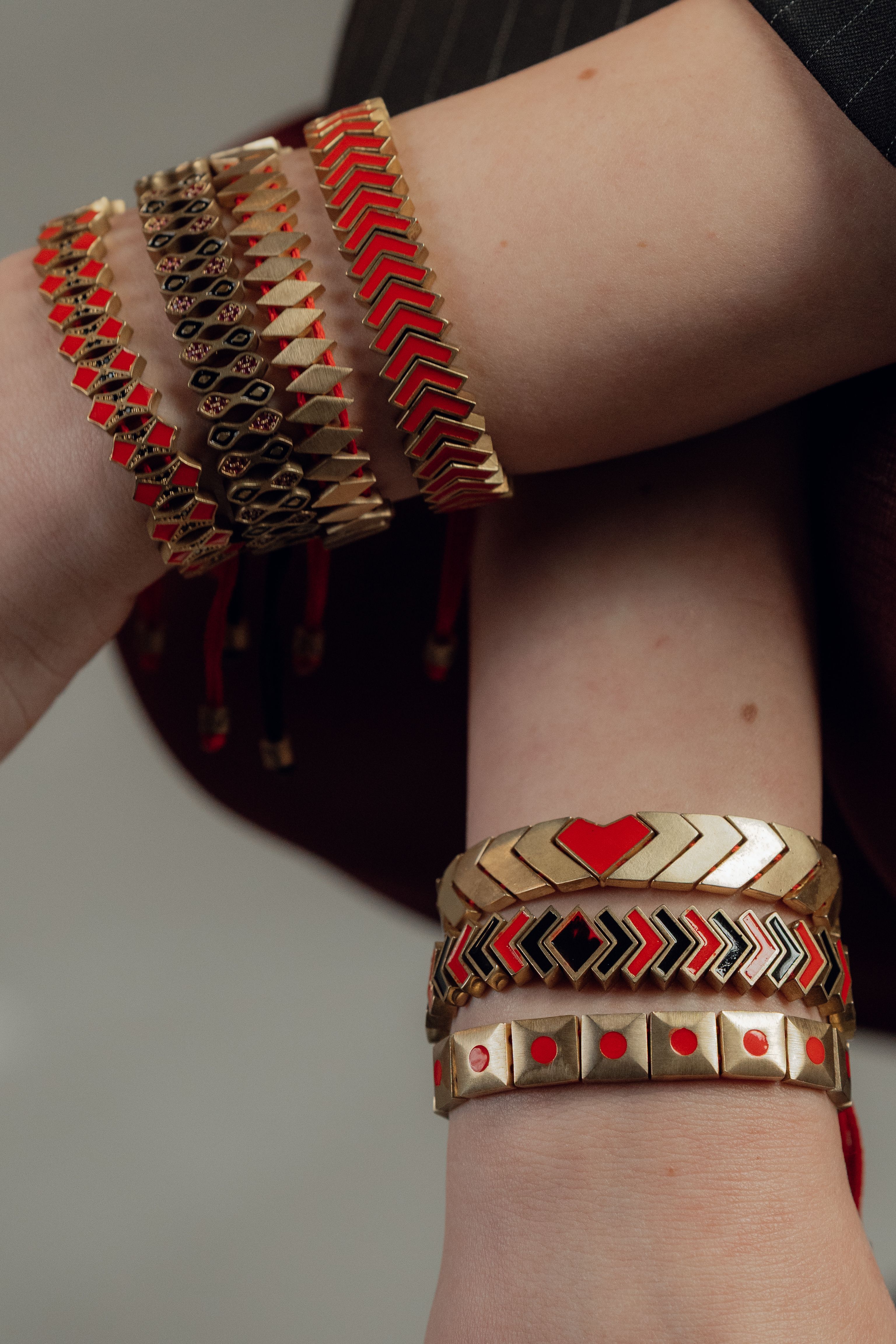 Close-up elegante de pulseiras vermelhas e douradas no pulso de uma pessoa, enfatizando acessórios de moda modernos.