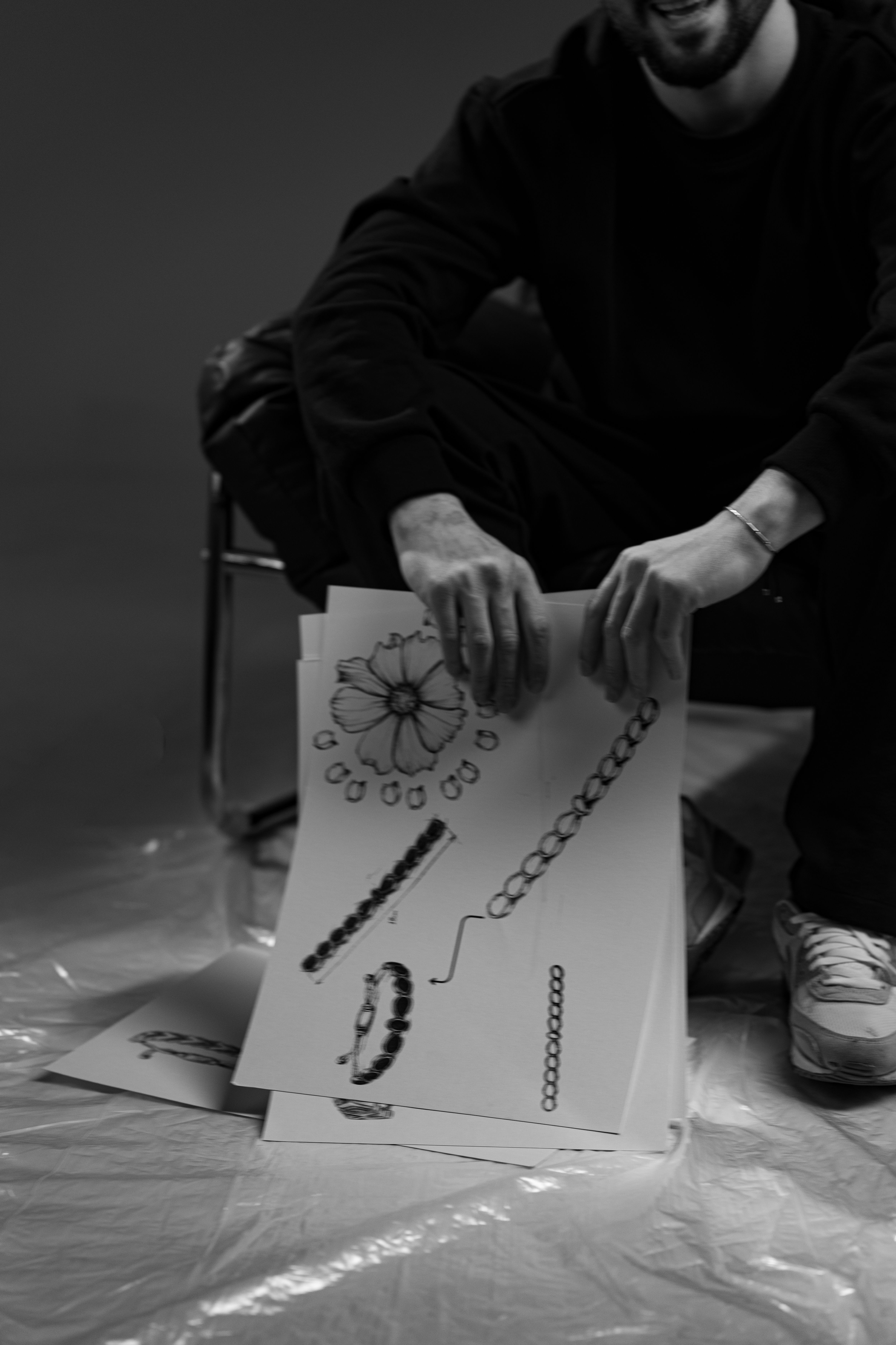 Black and white photo depicting a person holding detailed jewelry design sketches.