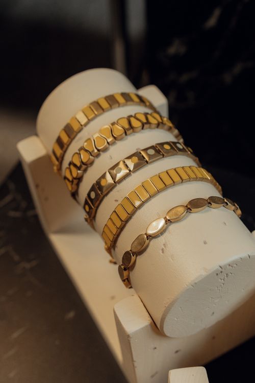 Free A collection of stylish gold bracelets elegantly arranged on a white display stand, perfect for jewelry showcases. Stock Photo
