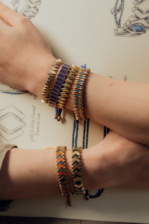 Free Close-up of hands showcasing stylish gold and blue bracelets against a design sketch background. Stock Photo