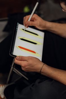 An adult sketching on a tablet with a stylus, focusing on design details.