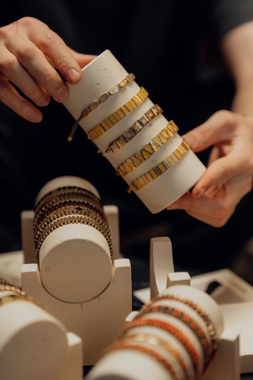 Free Close-up of hands displaying elegant gold and silver bracelets on a white display. Stock Photo