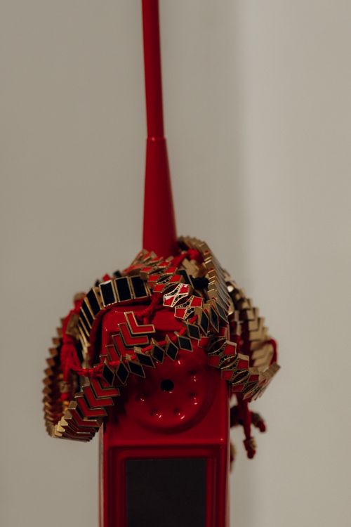 Free A vibrant red walkie-talkie ornately adorned with gold and black jewelry, creating an elegant fusion. Stock Photo