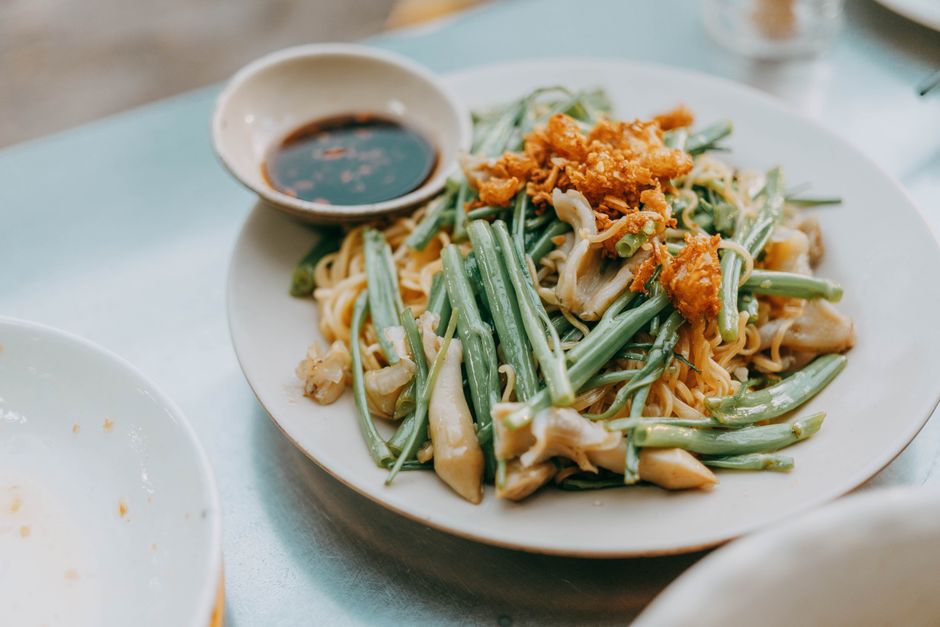 A bubbling casserole dish of green beans in creamy mushroom sauce topped with a golden layer of crispy fried onions, one corner scooped out with a serving spoon.
