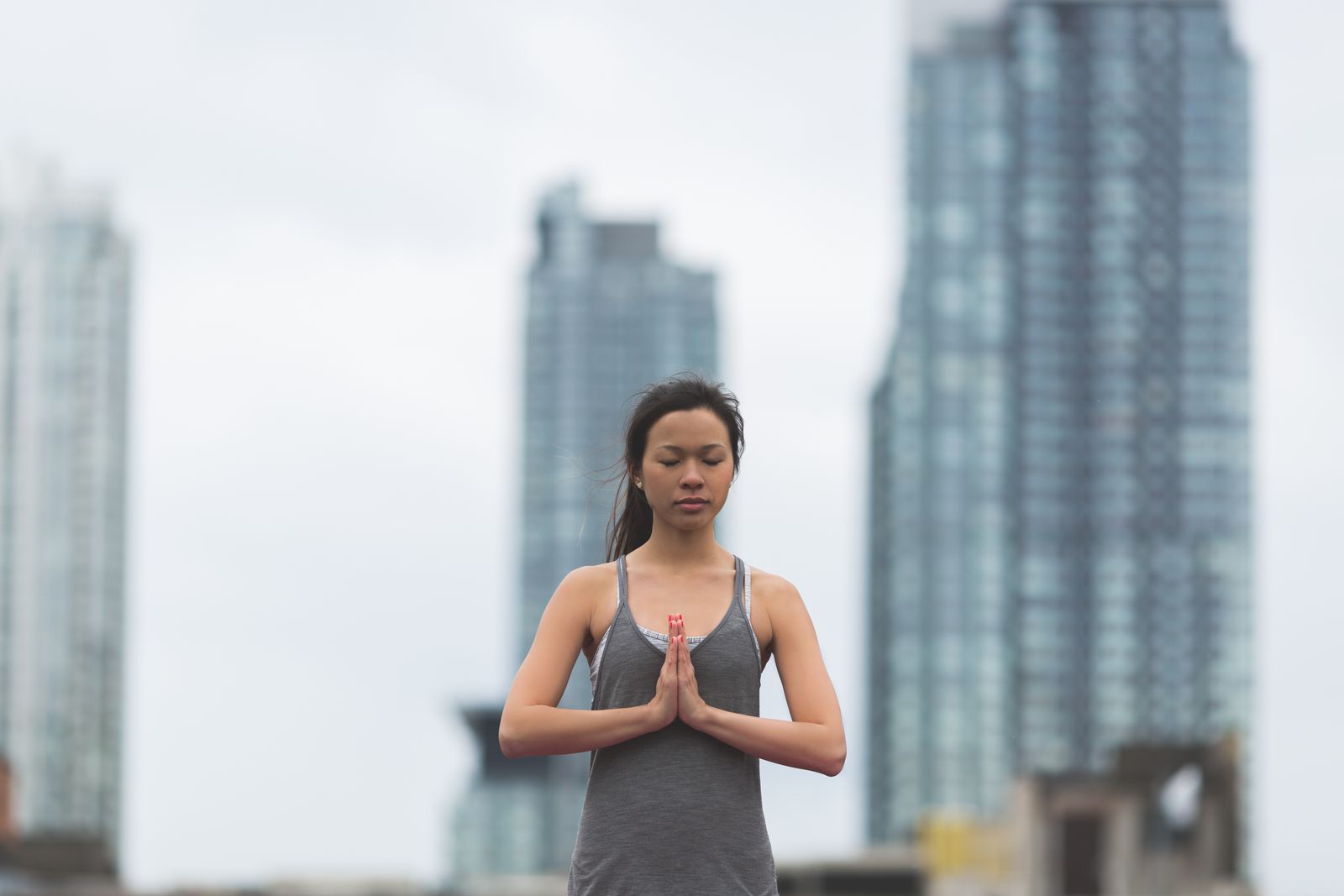 Woman practicing a yoga pose outdoors with a city skyline in the background