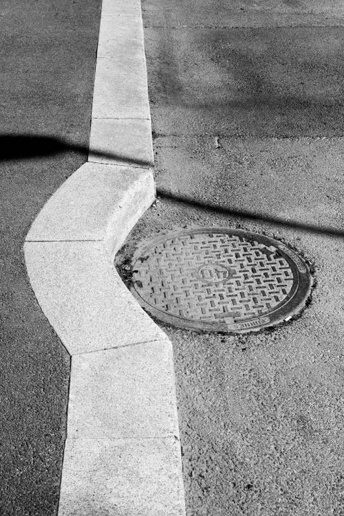 Free Artistic black and white photo of an urban manhole and curved sidewalk in Norway. Stock Photo