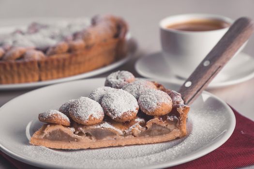 A tempting slice of apple pie with powdered sugar served alongside a cup of coffee.