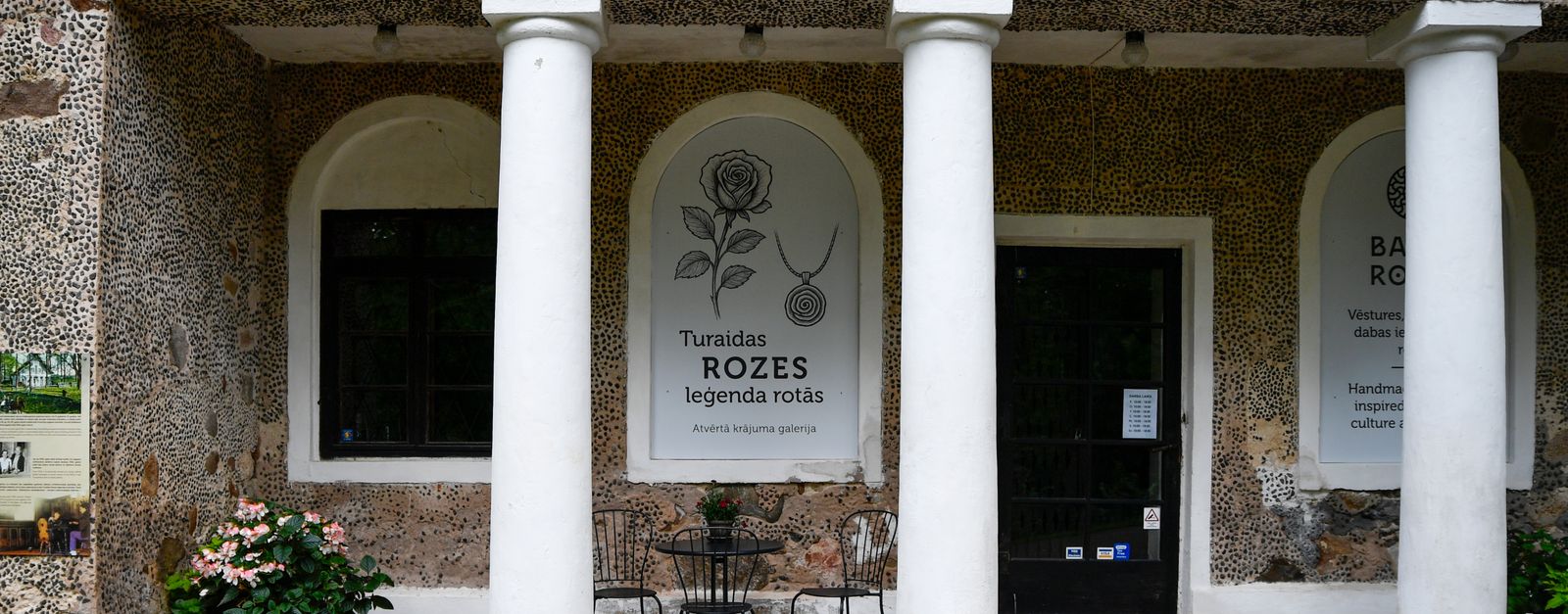 Historic stone building with columns and outdoor seating in Sigulda, showcasing Turaida Rose legacy.