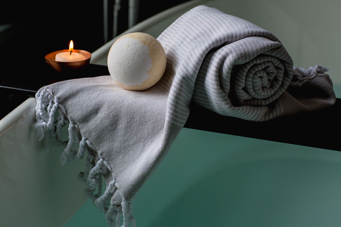 A serene bathroom scene with a lit candle, bath salts, and a folded towel