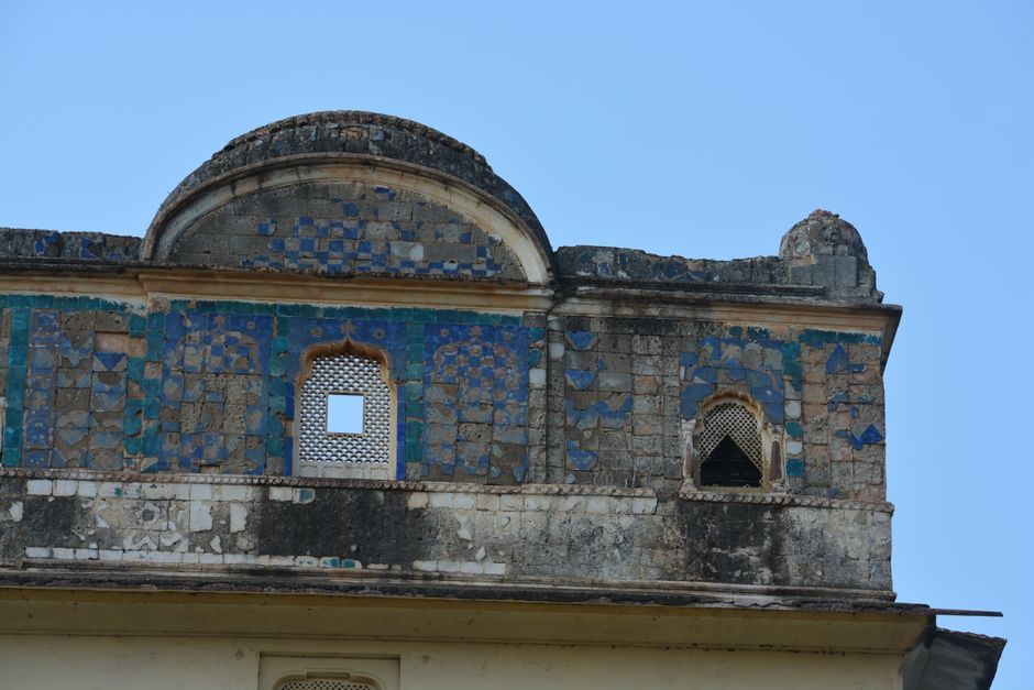 Detailed view of an ancient architectural structure with intricate mosaic design under clear blue sky.