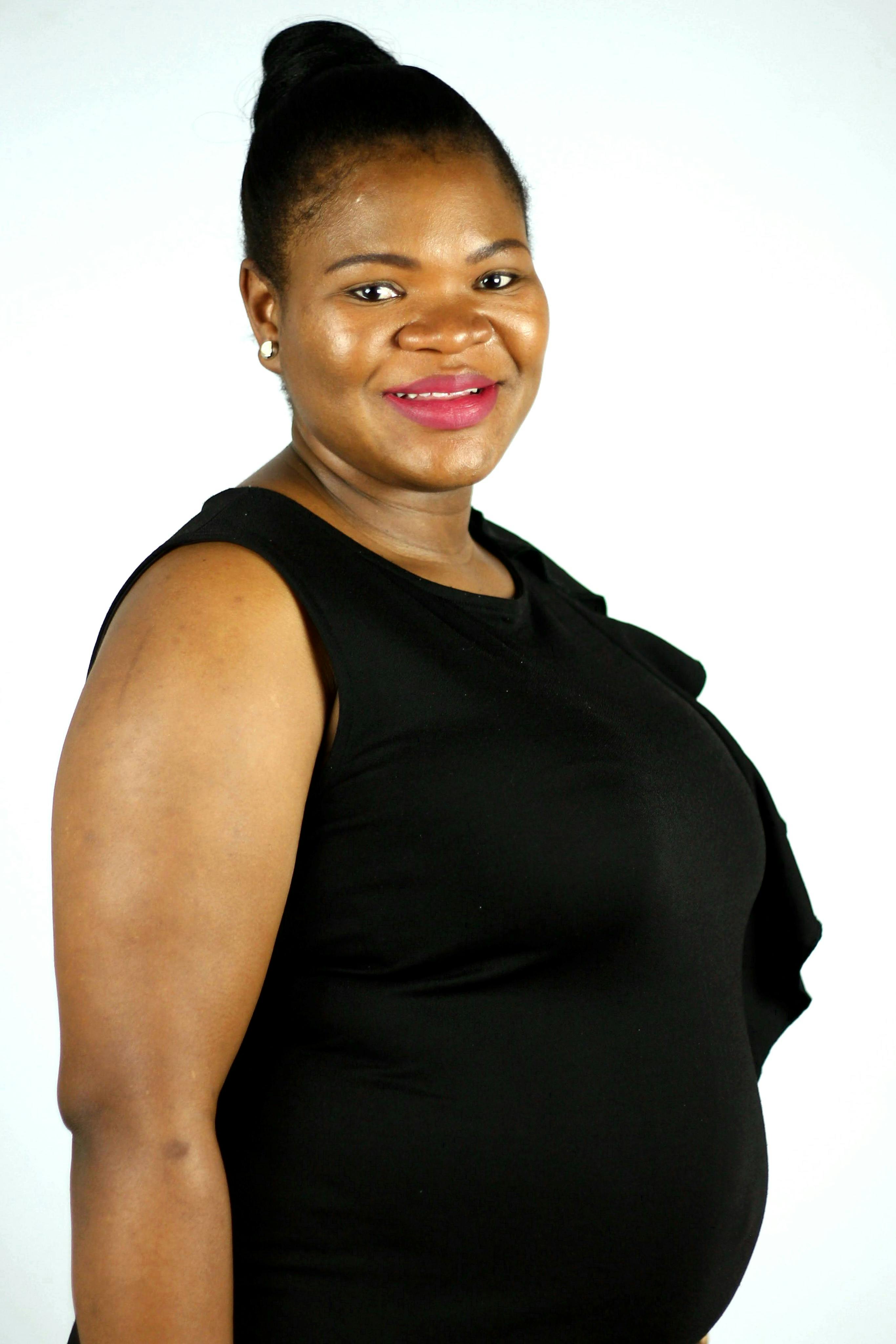 Portrait of a happy pregnant woman dressed in a black outfit, smiling warmly.
