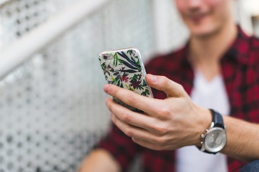 Close-up image of a person holding a smartphone in a floral case, focusing on lifestyle and technology.