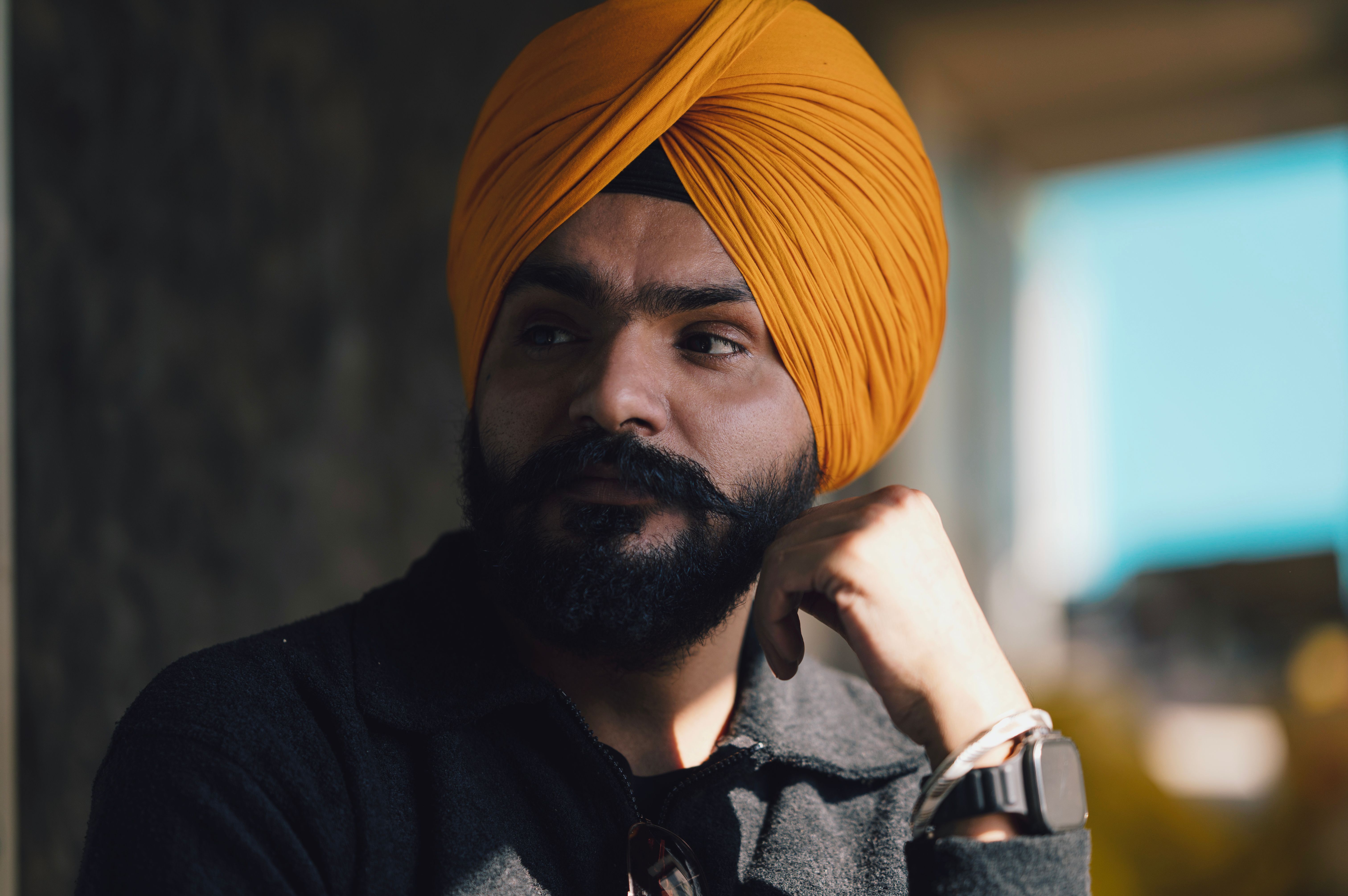 Stylish Sikh Man with Orange Turban in Thoughtful Pose · Free Stock Photo