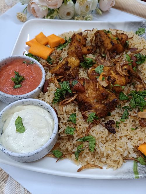 Free A mouth-watering biryani dish with flavorful chicken and fresh herbs, accompanied by sauces. Stock Photo