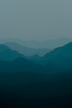 Peaceful layers of blue mountains at dawn with a misty atmosphere.
