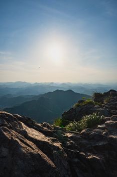 Stunning mountain landscape with rugged rocks and lush greenery under a bright sunlit sky.