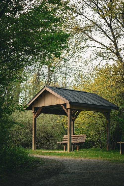 Free A peaceful wooden gazebo in a lush forest during spring, ideal for relaxation. Stock Photo
