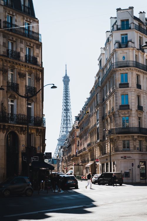 Free A picturesque street in Paris showcasing classic architecture with the iconic Eiffel Tower in the background. Stock Photo