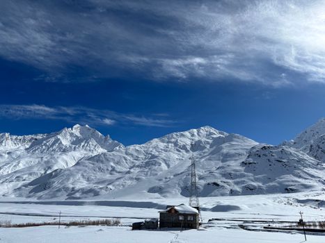 Scenic view of snowy Himalayas in Zanskar Valley with blue sky and cirrus clouds.