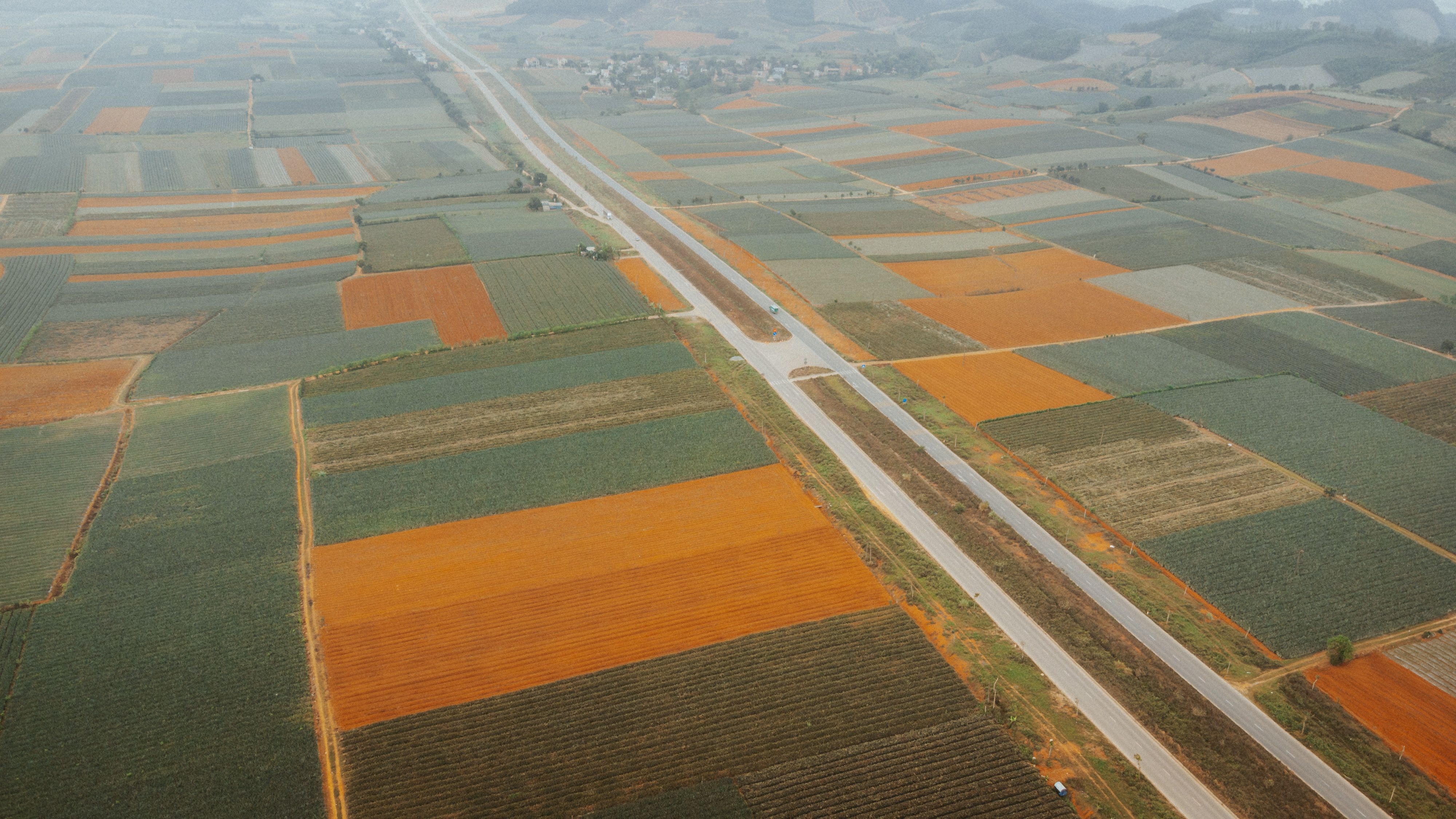 Aerial view of colorful patchwork farmlands in Vietnam, showcasing diverse crops and landscapes.