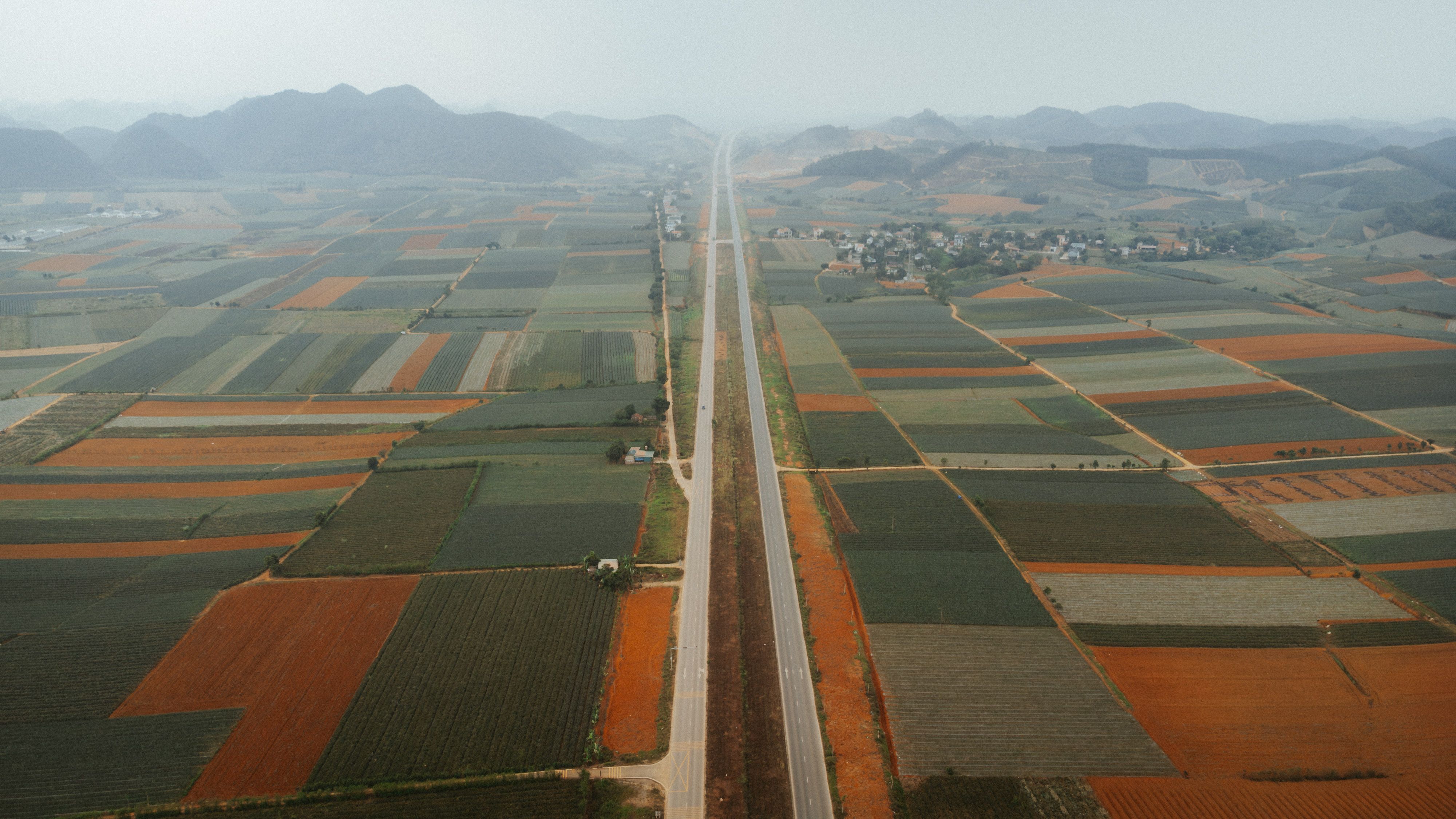 An aerial view of expansive patchwork farmland with a highway in Vietnam.