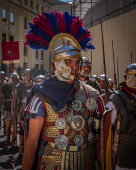 Roman legionary in full armor participates in a historical reenactment parade with fellow soldiers.