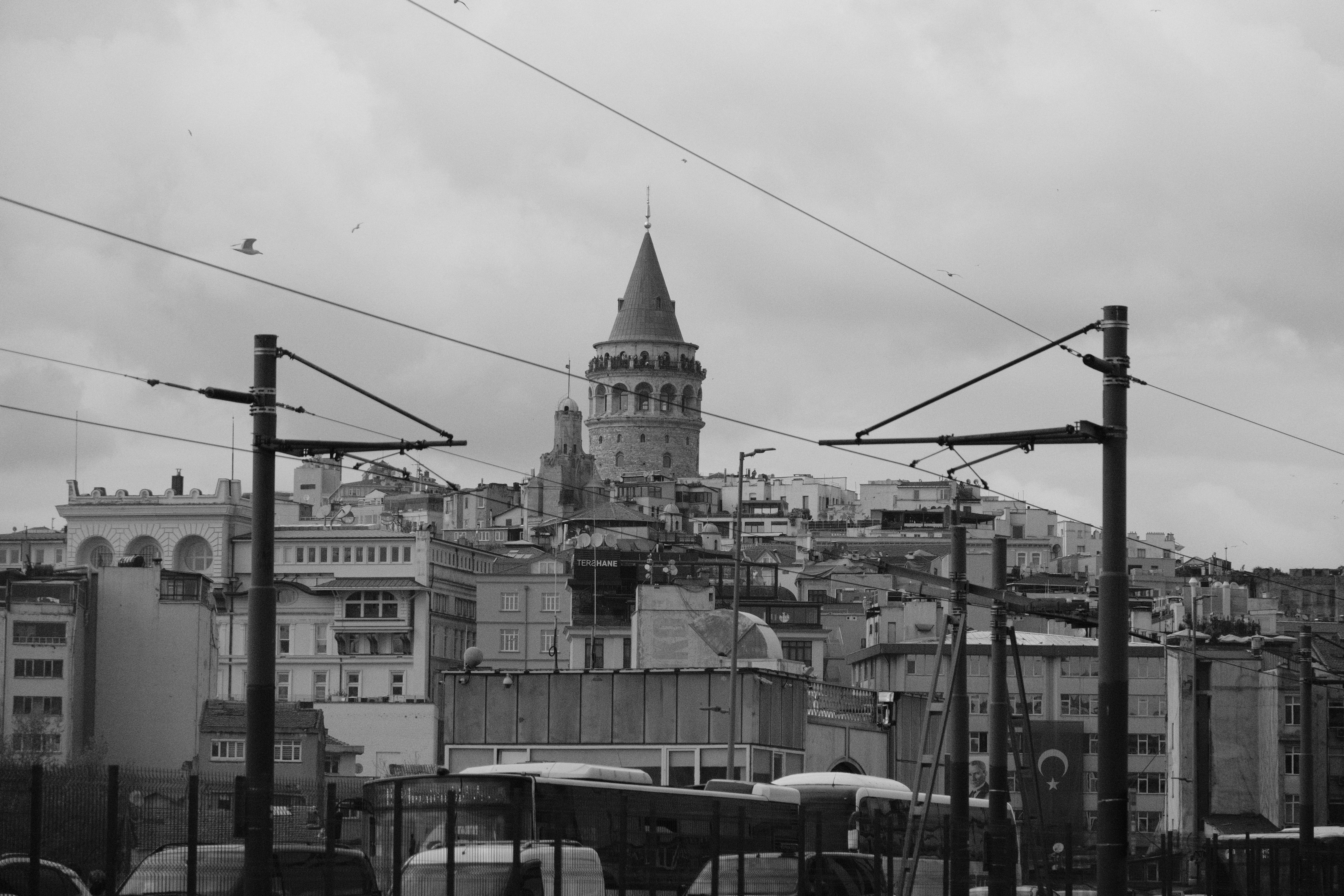 A dramatic black and white cityscape showcasing Istanbul's iconic Galata Tower under cloudy skies.