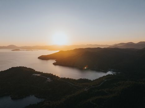 Breathtaking aerial sunset view over the tranquil sea and lush Turkish landscapes.
