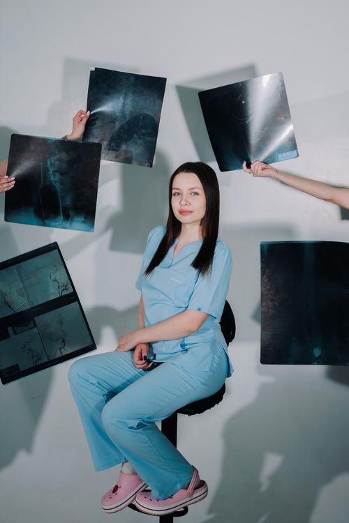 Free Female healthcare worker in blue scrubs surrounded by X-ray scans, depicting medical diagnostics. Stock Photo