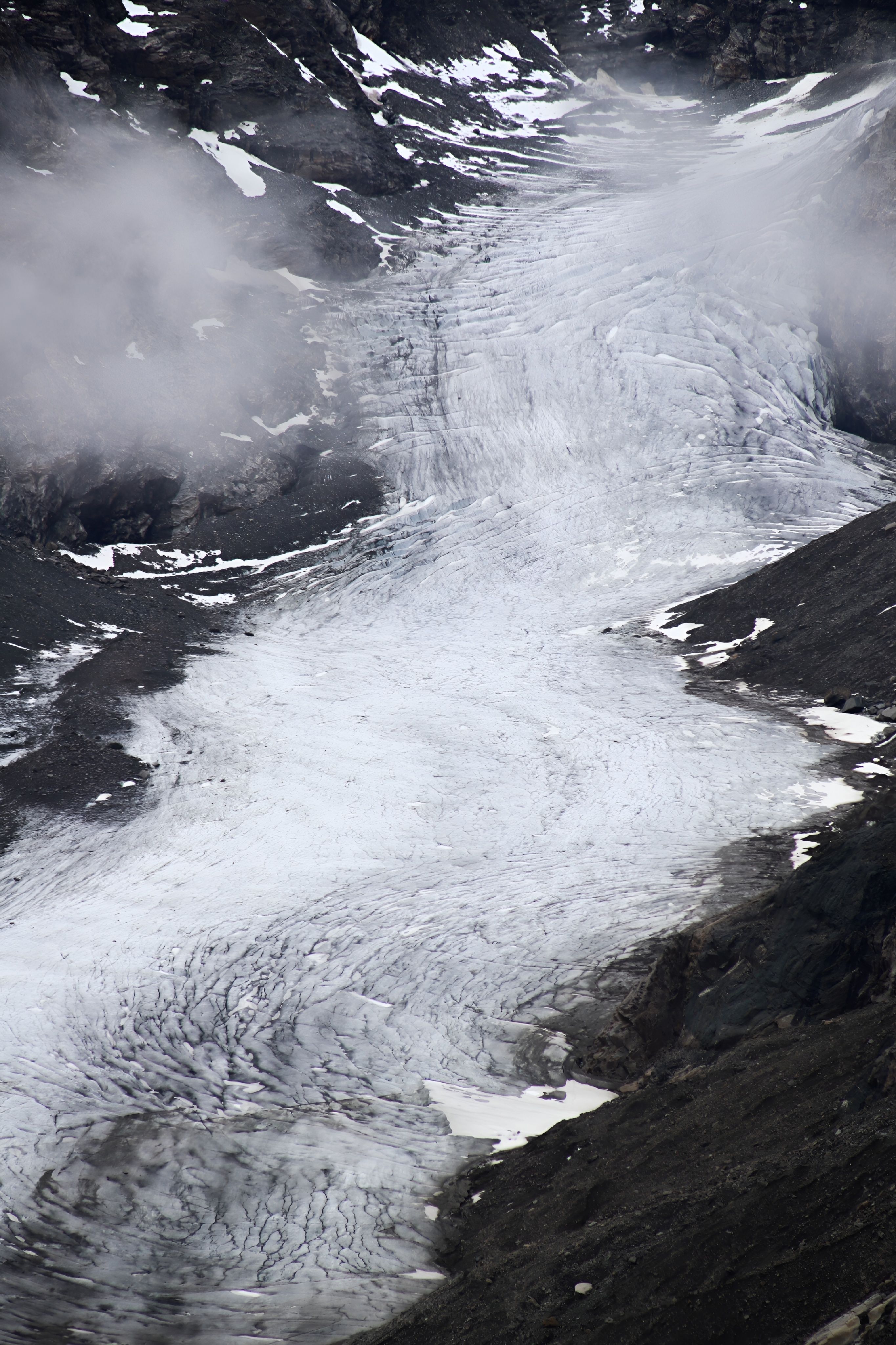 A stunning view of a glacier among rocky, mist-covered mountains.
