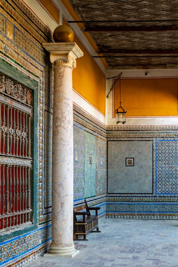 Explore the intricate Mudejar architectural style in a historic Seville courtyard with decorative tiles and columns.
