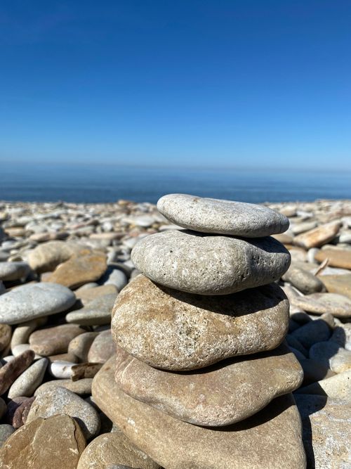 Free A peaceful stack of pebbles on a rocky Estonian beach with clear blue skies. Stock Photo